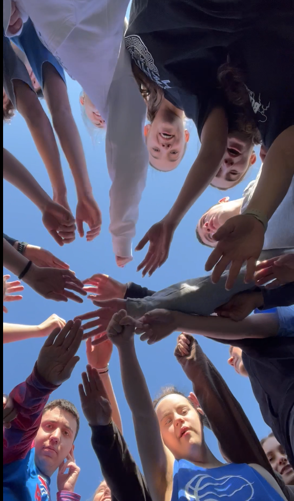 A group of people holding handsDescription automatically generated with medium confidence